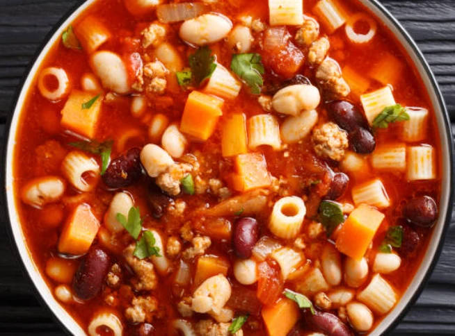A bowl of classic Italian minestrone soup loaded with vegetables, cannellini beans, and pasta, topped with grated Parmesan and served with crusty bread