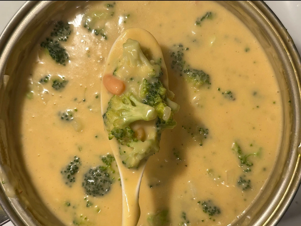Creamy broccoli cheddar soup in a bowl with broccoli florets and shredded cheddar