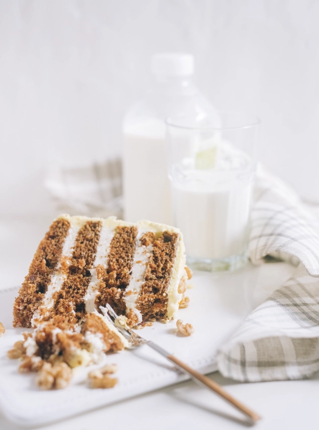 Carrot honey cake with cream cheese frosting and a slice showing the golden crumb