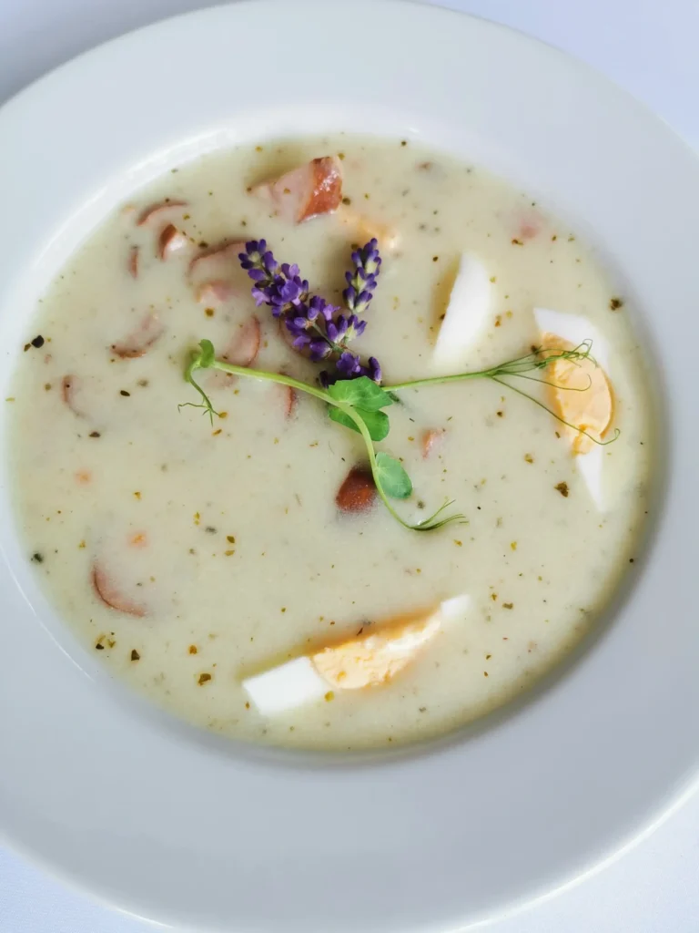 Polish zurek soup in a bread bowl with white sausage and hard-boiled egg