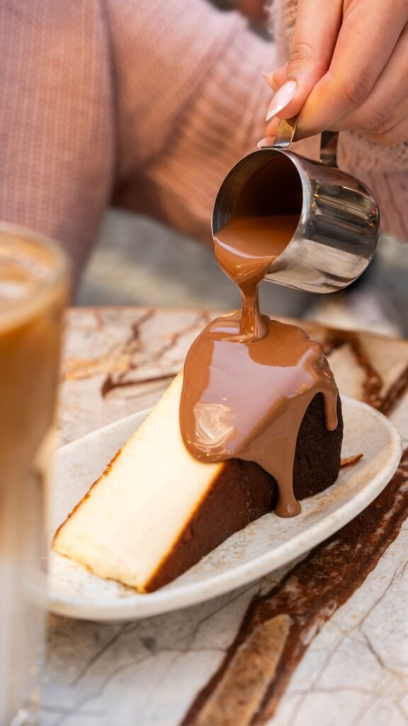 Warm sauce poured over a slice of Basque cheesecake