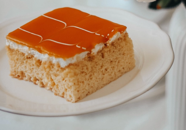 Tres leches cake topped with whipped cream showing the milk-soaked sponge