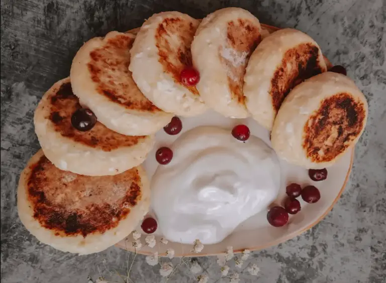 Golden Ukrainian cheese pancakes (syrnyky) with a dollop of sour cream