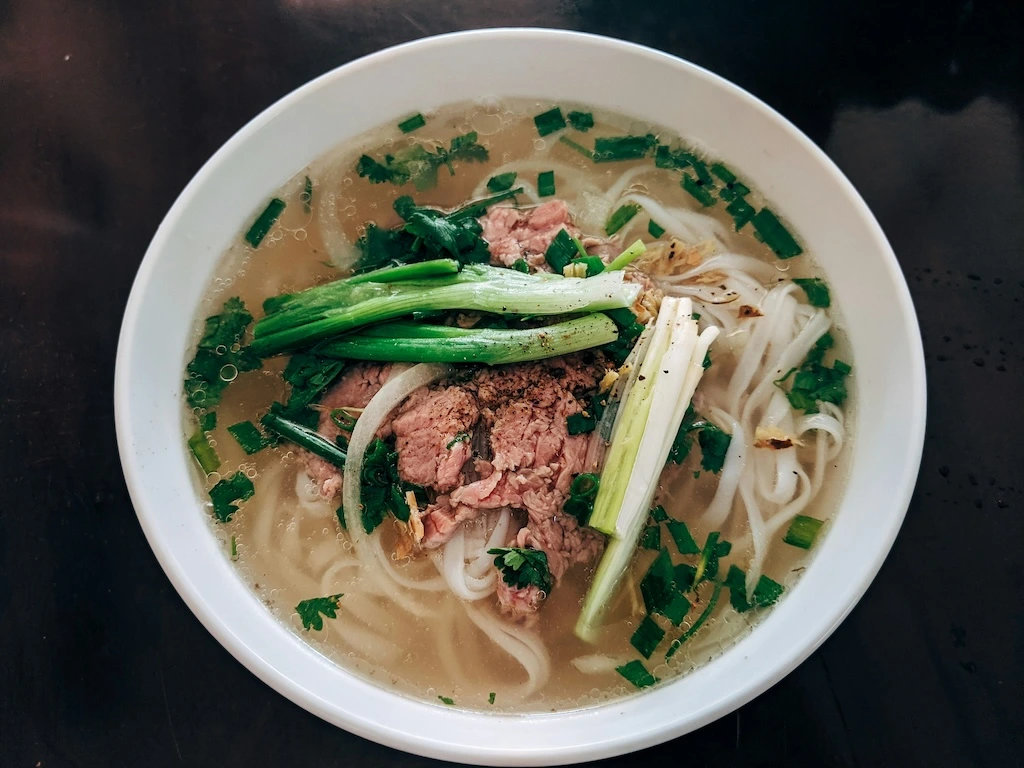 Vietnamese beef pho bowl with thin beef slices, rice noodles and fresh herbs